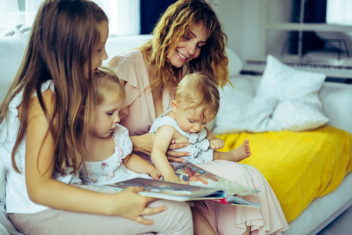 mother with three children reading a book in a homely atmosphere, sharing time with parents and chil