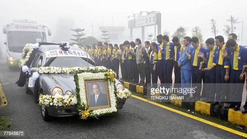 Genting employees (R) pay their last respects as a hearse bearing the coffin of late gaming tycoon L